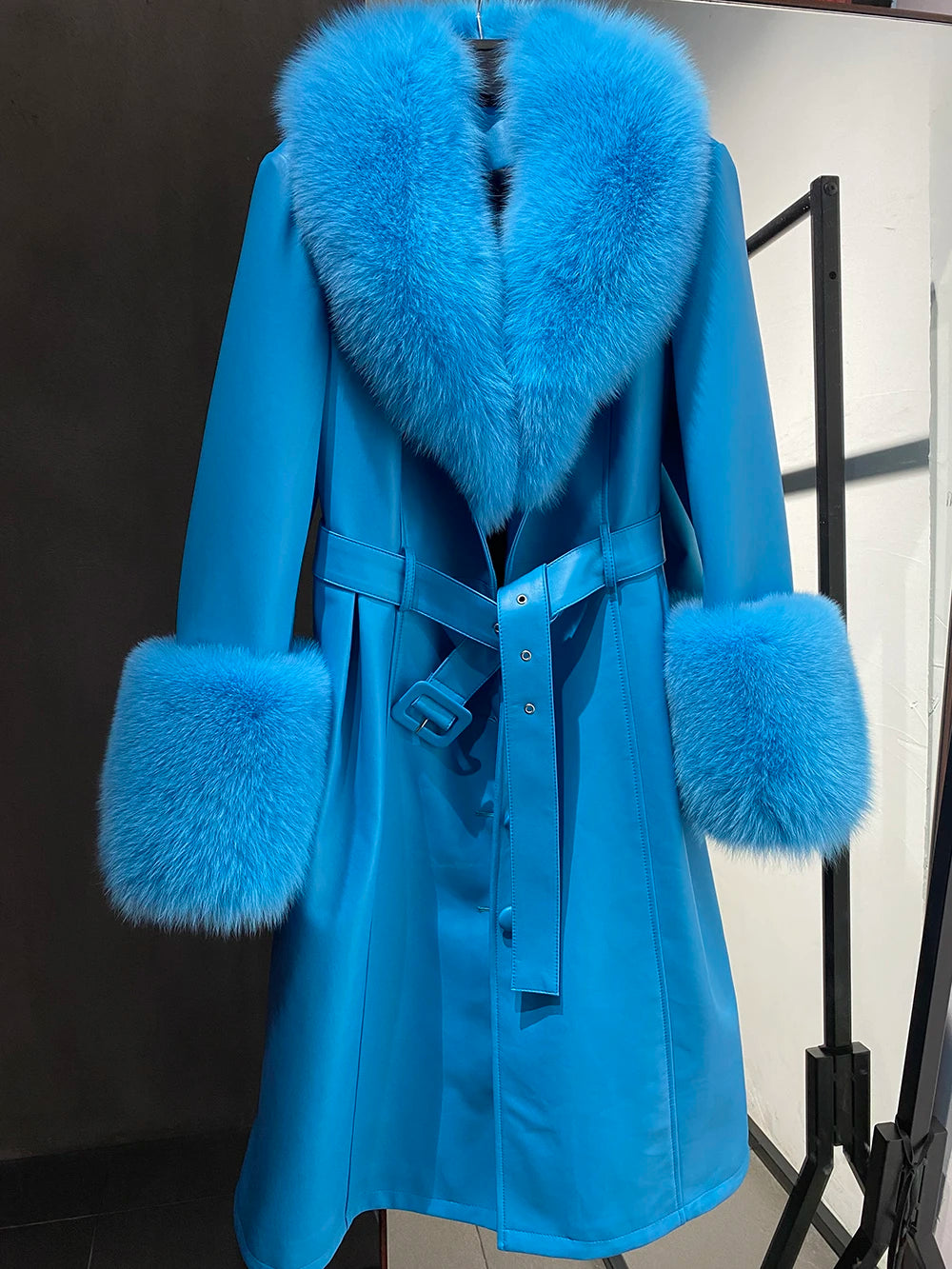 Blue coat with fur trim on a mannequin against a black background