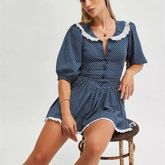 Woman wearing a blue polka dot dress with white lace trim on a white background
