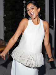 Woman wearing a white sleeveless top with fringe details outdoors.