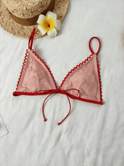 Close-up of a pink lace bikini top with red trim and tie closure