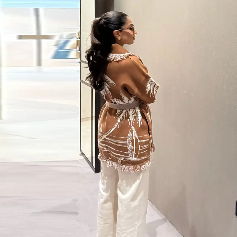 Woman wearing a stylish outfit with a backless top and white pants in an indoor setting.