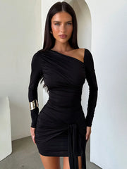Woman wearing a black one-shoulder dress with long sleeves in a minimalistic setting.