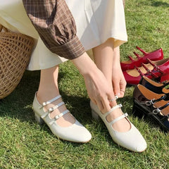  A woman wearing square toe Mary Jane pumps with a buckle strap, showcasing their elegant design. White. Golden Atelier 2