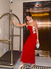 Woman in a red strapless dress with white floral details standing next to an elevator.