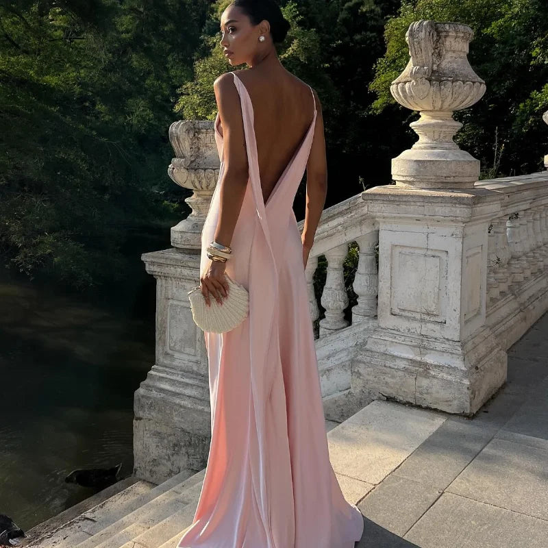 Woman in a pink evening gown standing on a stone pathway with trees in the background