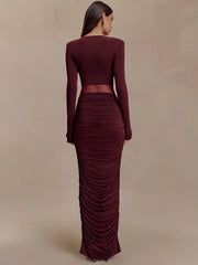 Maroon two-piece outfit with long sleeves and ruched skirt on a beige background