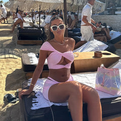 Model wearing pink twisted cutout swimsuit and skirt on the beach