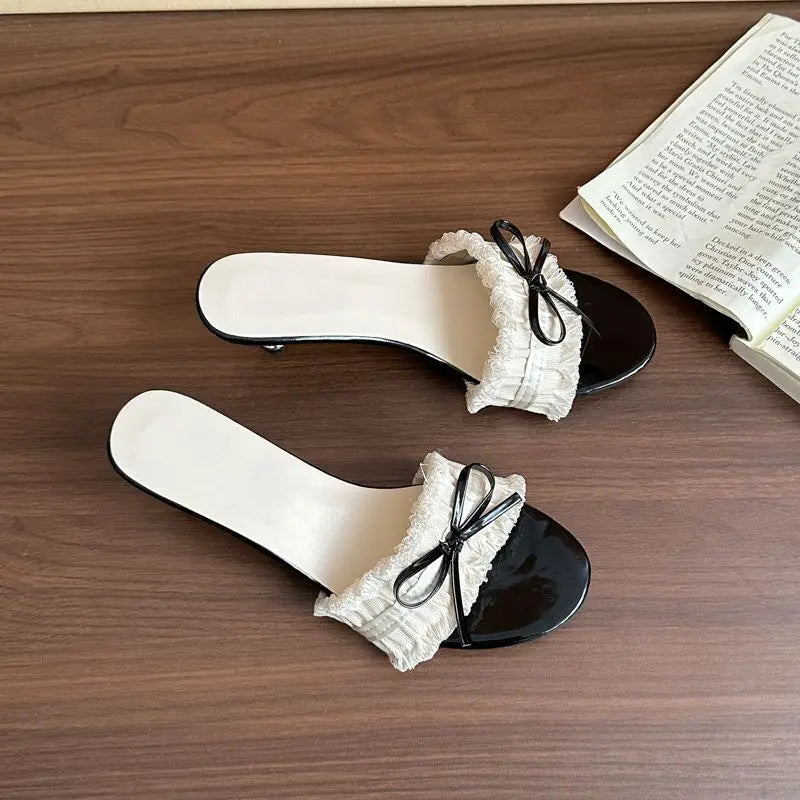 Side view of bow heeled slide sandal