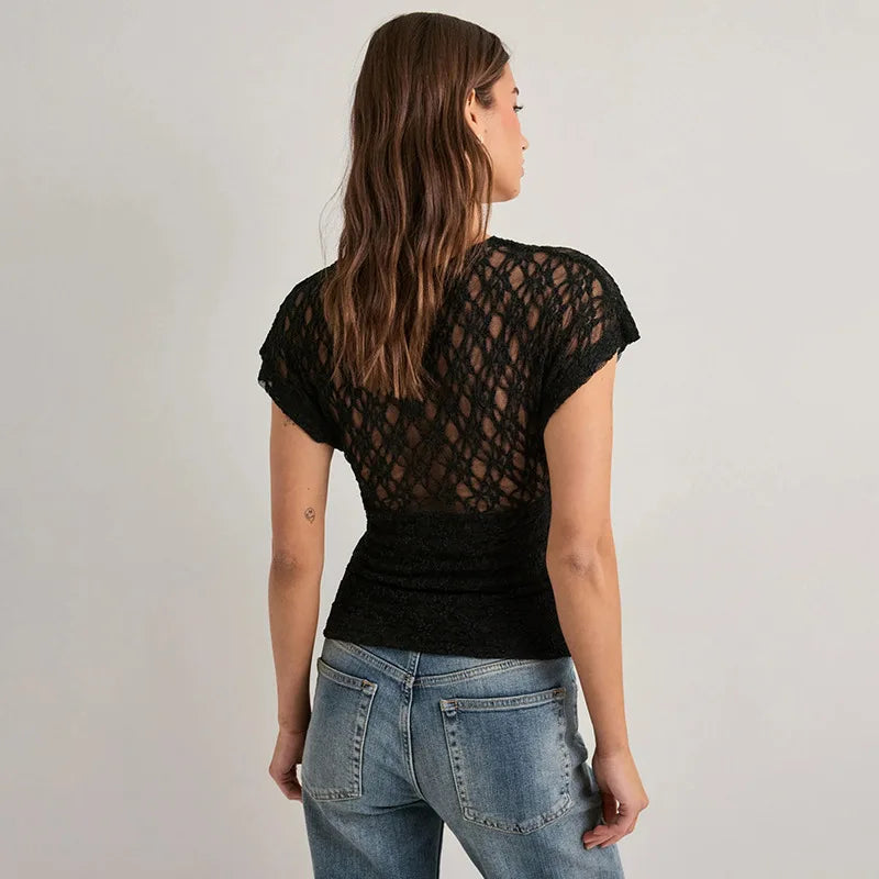 Woman wearing a black lace-back top and blue jeans on a plain background