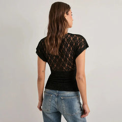 Woman wearing a black lace-back top and blue jeans on a plain background