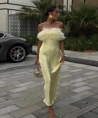Woman in a yellow off-shoulder dress with feather details walking outdoors.