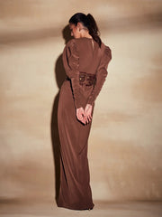 Woman wearing a long brown dress against a beige background