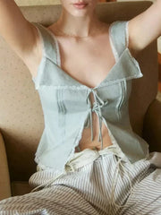 Woman wearing a light blue lace-trimmed top and striped pants on a beige couch.