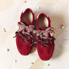 Red suede low-top sneakers with dual-layered bow laces and white accent.