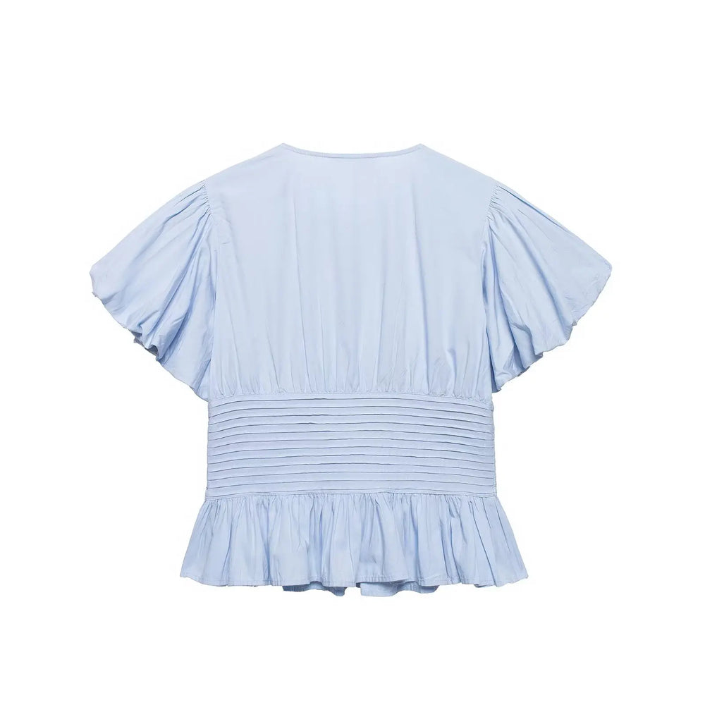 Light blue blouse with ruffled sleeves and bottom on a white background