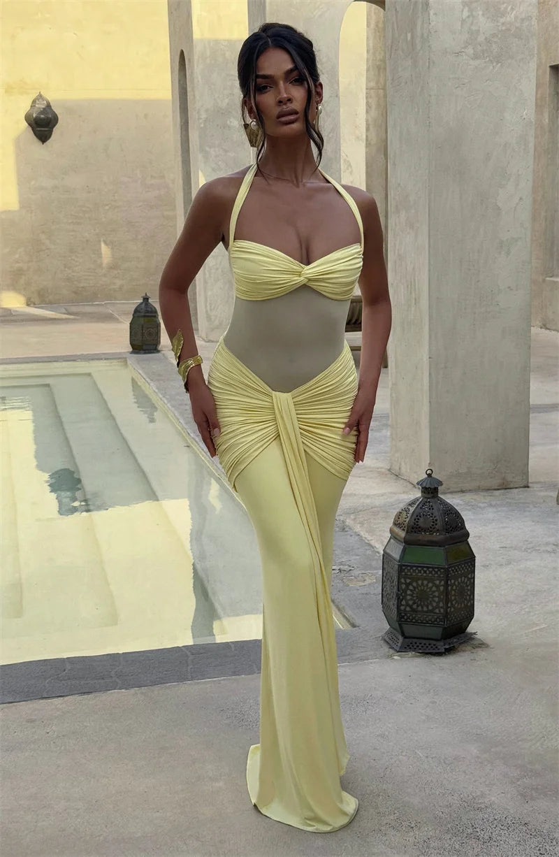 Woman in a yellow evening gown standing in an outdoor setting with architectural elements.