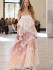 Model wearing a layered dress with lace details on a runway.