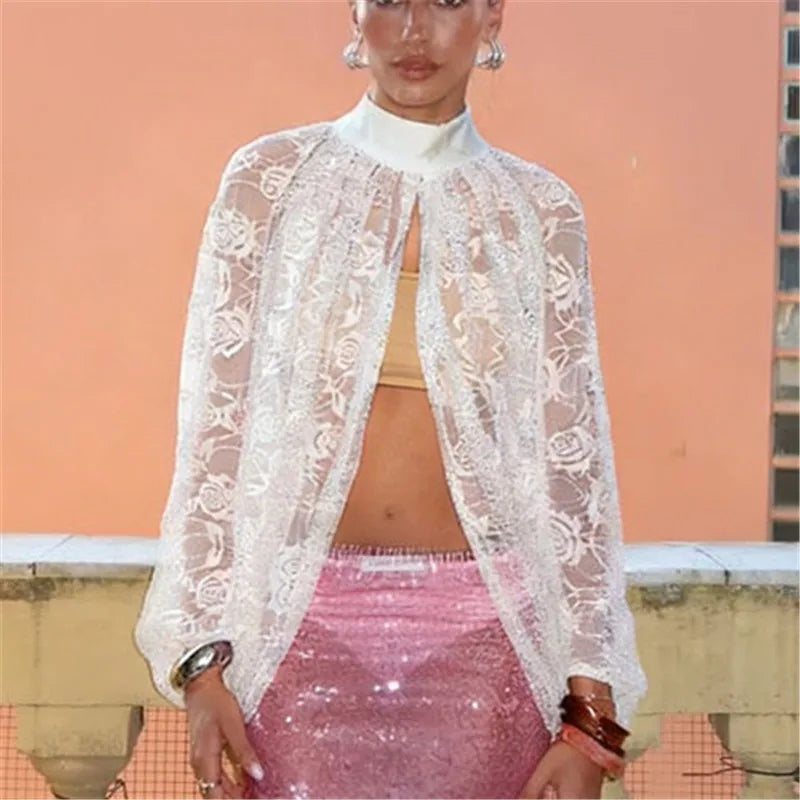 Person wearing a white lace top over a pink skirt with a peach-colored wall background