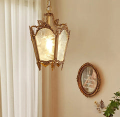 Decorative pendant light hanging on a wall with a mirror and plant in the background