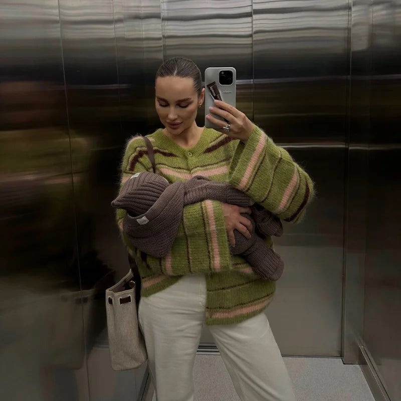 Woman holding a baby while wearing a green striped knit cardigan