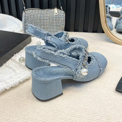 Denim block heel sandals with pearls styled beside crystal clutch