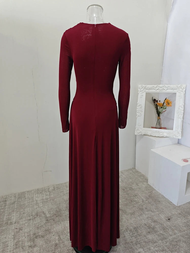 Maroon dress on a mannequin against a white wall with a small framed picture of flowers.