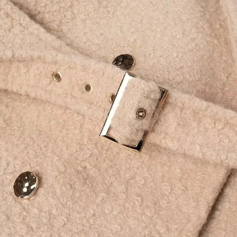 Close-up of a beige fabric surface with metal buttons and a rectangular metal clip.