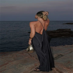Woman in a black dress standing by the ocean at dusk