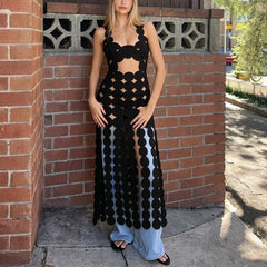 Black cut out dot mesh maxi dress worn against a brick wall with jeans