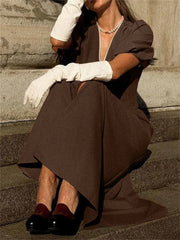 Person wearing a brown dress with white gloves sitting on stone steps.