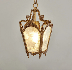 Decorative pendant light with ornate gold fixture and glass shade on a gray background