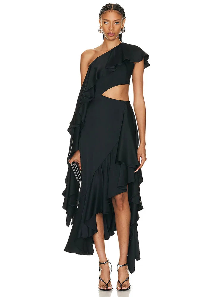 Woman wearing a black one-shoulder dress with ruffle details on a white background