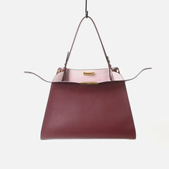 Leather trapezoid top handle bag with a pink interior.
