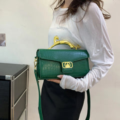 Green embossed top handle bag held by a woman