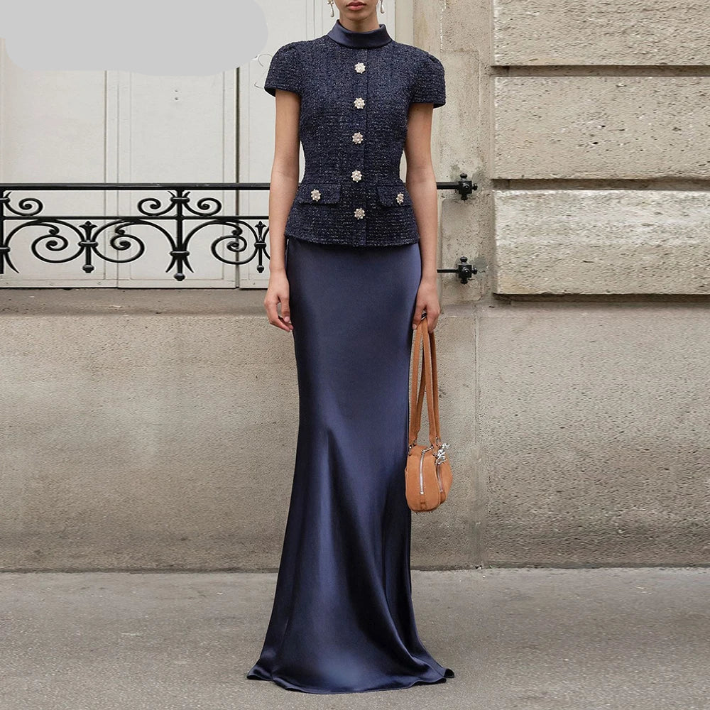 Woman wearing a navy two-piece set featuring a short-sleeve buttoned top and floor-length sheath skirt — elegant summer office or event outfit