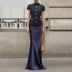 Woman wearing a navy two-piece set featuring a short-sleeve buttoned top and floor-length sheath skirt — elegant summer office or event outfit