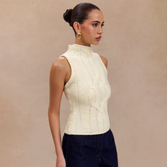 Woman wearing a cream knitted sleeveless top against a beige background