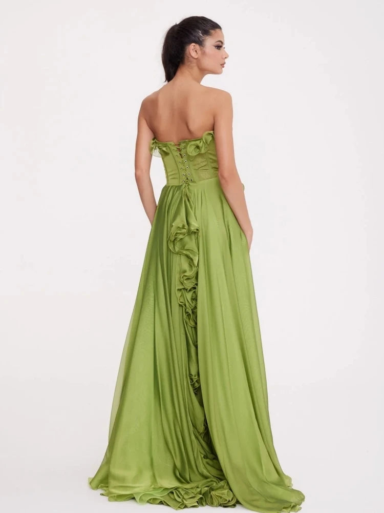 Woman wearing a green strapless gown with ruffled details on a white background