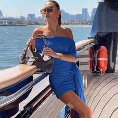 Woman in a blue dress on a boat with a city skyline in the background