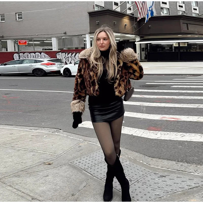 Woman in a leopard print coat and black outfit standing on a city street.
