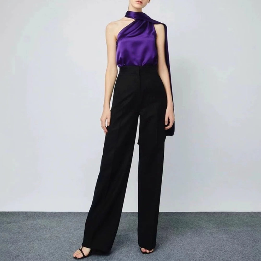 Person wearing a purple top and black pants on a plain background