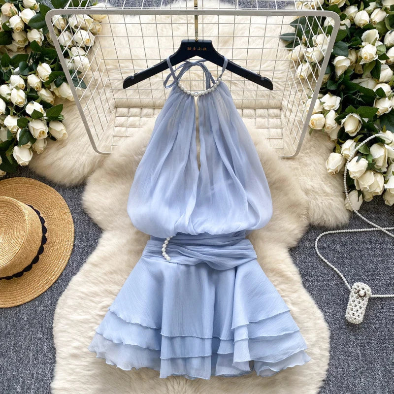 Light blue dress on a hanger with floral decorations and a hat in the background