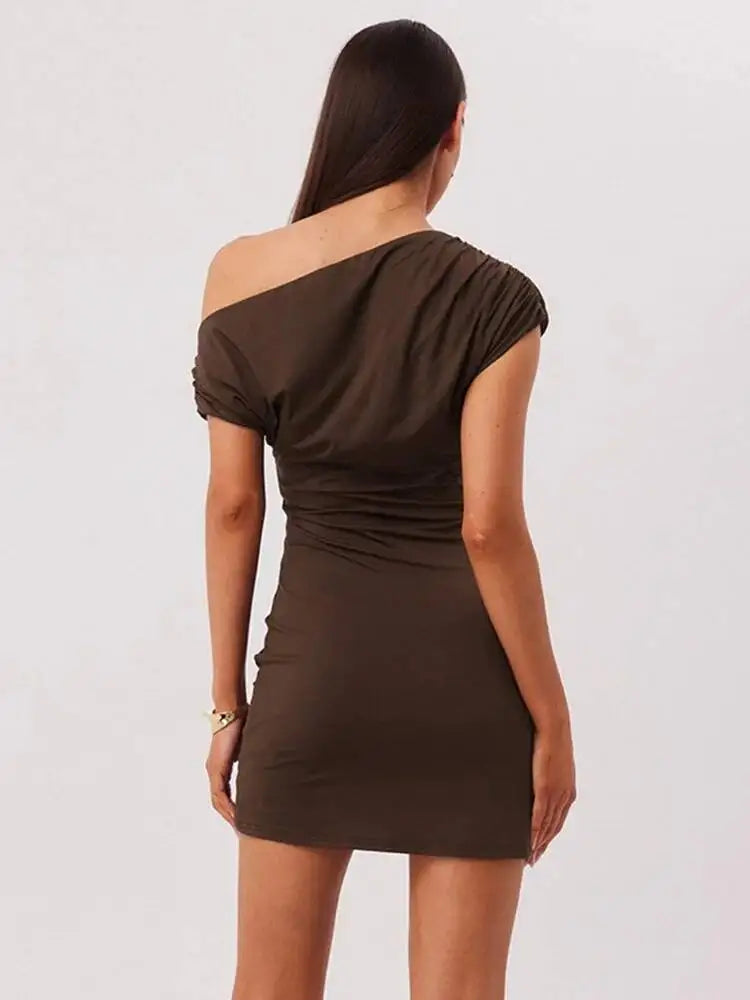 Woman wearing a brown off-shoulder dress against a plain background