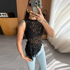 Person wearing a black lace top and light blue jeans indoors.