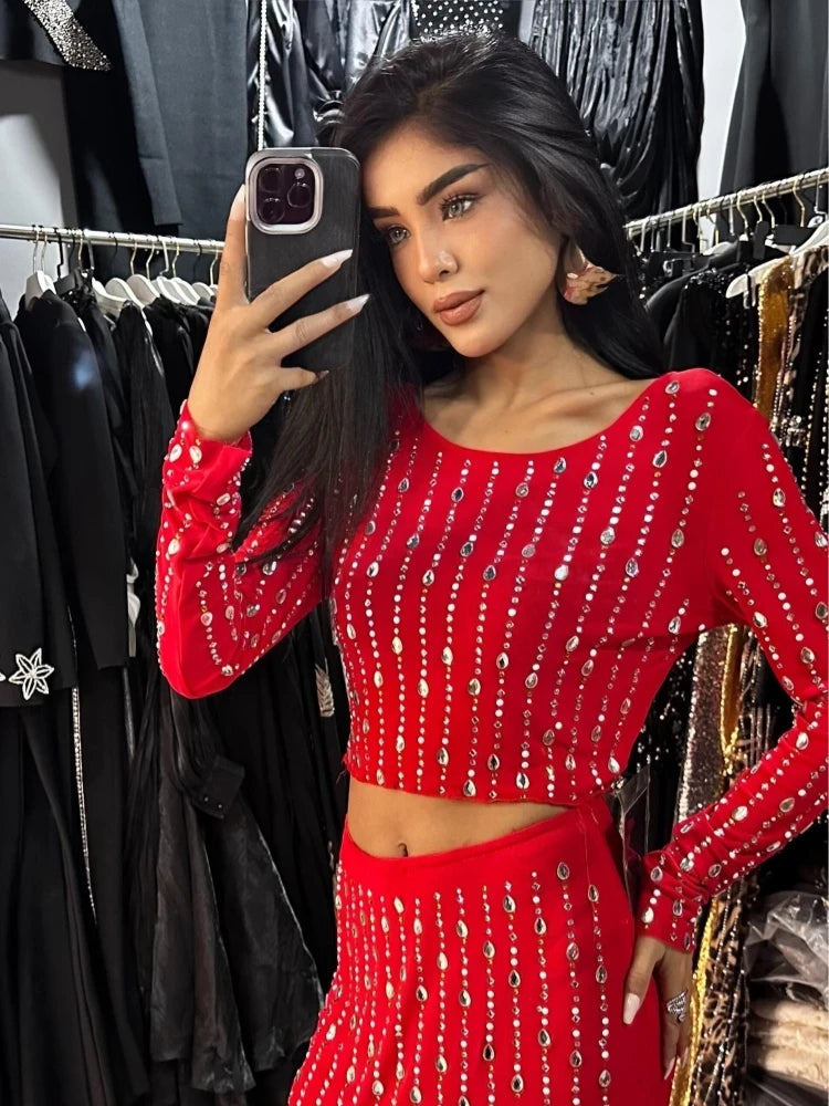 Woman in a red beaded outfit taking a mirror selfie in a clothing store.