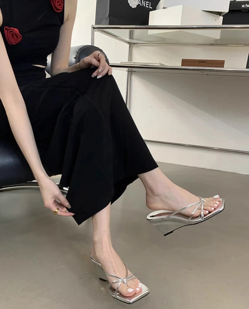 Person wearing black pants and transparent sandals in a store setting