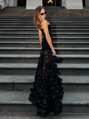Woman in a black floral gown standing on steps