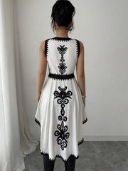White dress with black floral patterns worn by a person against a plain background