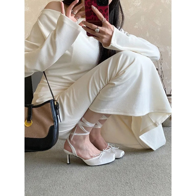 Person wearing white shoes with sheer design, sitting on a couch.