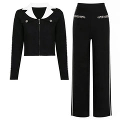 Black knit jacket with white collar and embellished sleeves, paired with wide-leg black trousers with white side stripes.